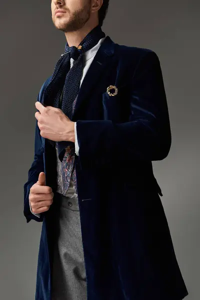 A handsome man dressed in a velvet coat and scarf exudes charm and sophistication indoors. — Stock Photo