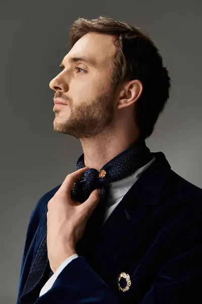 A dapper man elegantly styles his scarf, showcasing confidence and charm indoors. — Stock Photo