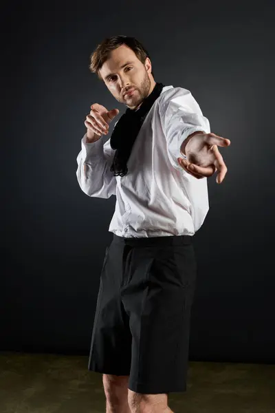 A dandy in elegant attire showcases charisma while striking a dynamic pose against a dark backdrop. — Stock Photo