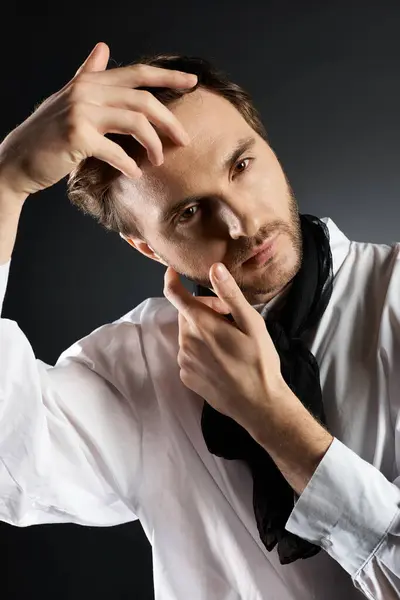 A dapper individual styles his hair while posing against a sleek, dark backdrop. — Stock Photo