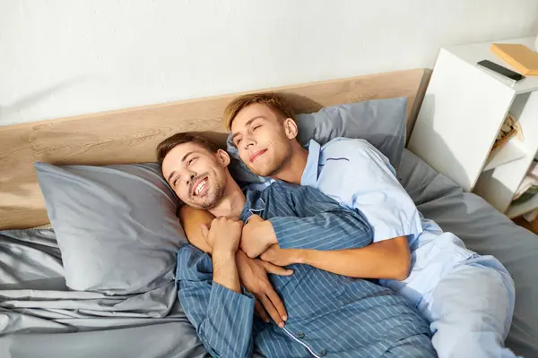 A joyful gay couple in pajamas shares affectionate moments in their warm morning routine together. — Stock Photo