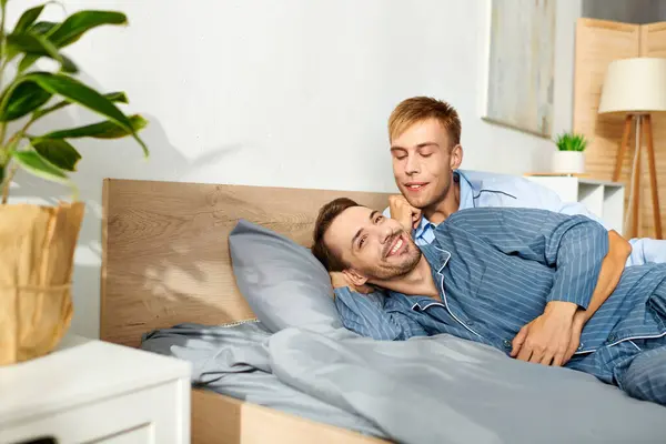 Un couple gay affectueux partage un câlin matinal joyeux dans leur pyjama confortable, profiter de l'autre compagnie. — Photo de stock