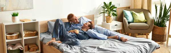 Ein glückliches homosexuelles Paar entspannt sich an einem sonnigen Morgen im Bett und teilt Lachen und Wärme im Schlafanzug. — Stockfoto