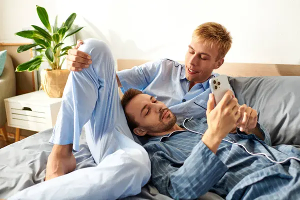 Dois homens de pijama compartilham uma manhã terna, sorrindo e desfrutando da companhia uns dos outros enquanto relaxam na cama. — Fotografia de Stock