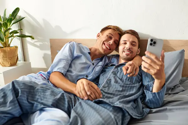 A cheerful couple in pajamas cuddles and enjoys each others company while sharing a moment in their cozy bedroom. — Stock Photo