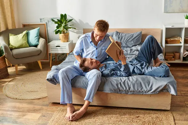 A joyful morning spent as a gay couple relaxes in pajamas, sharing affection and reading together. — Stock Photo