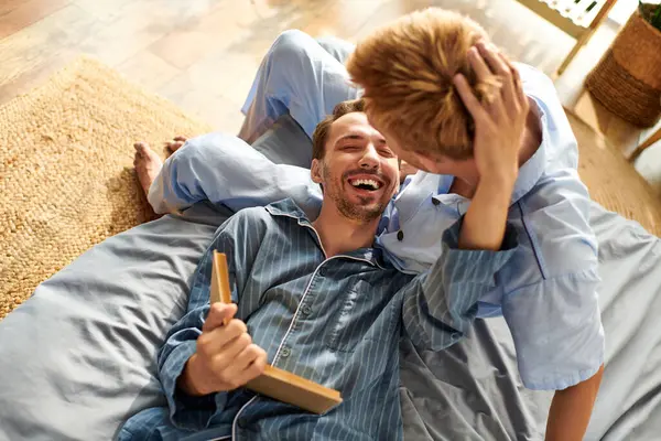 Una coppia gay amorevole gode di una mattinata gioiosa insieme, condividendo risate e calore in pigiama. — Foto stock