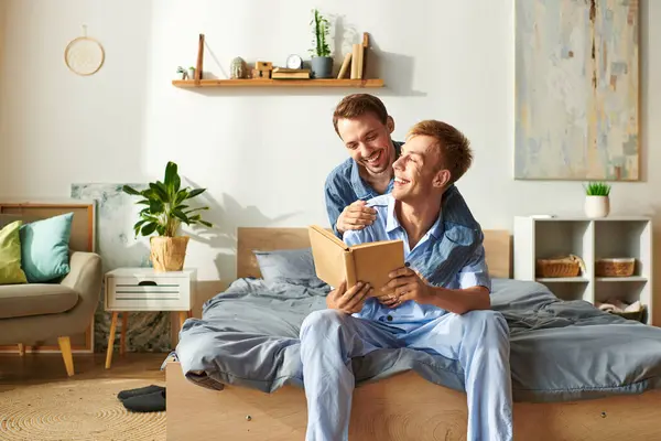 A happy couple shares laughter and warmth while reading together in their cozy morning pajamas. — Stock Photo