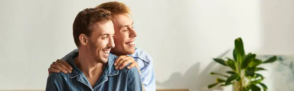 A joyful gay couple embraces each other in pajamas, sharing love and laughter in the warmth of their home. — Stock Photo