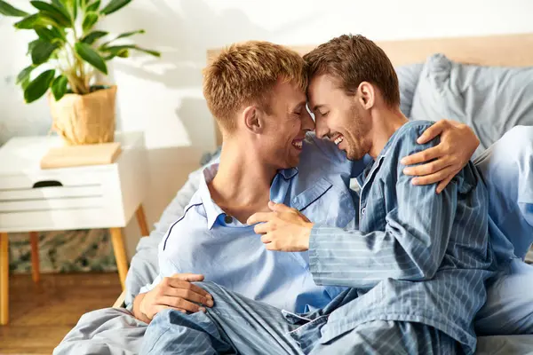 Un amorevole coppia gay gode di un accogliente mattina, sorridente e ridente mentre immerso insieme in pigiama. — Foto stock