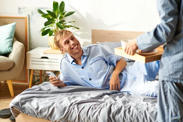 A joyful gay couple enjoys a leisurely morning in their pajamas, sharing warmth and affection in bed. — Stock Photo