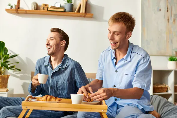 A joyful morning as a loving couple shares breakfast together in their cozy pajamas, filled with laughter. — Stock Photo