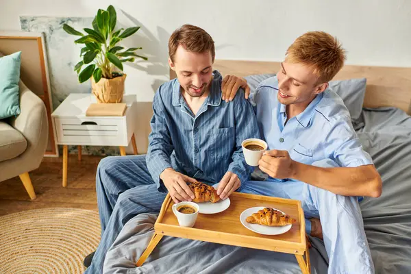 Two men enjoy a lovely morning together, sharing breakfast in their pajamas and sipping coffee joyfully. — Stock Photo