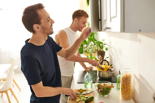 Two men happily prepare a fresh salad together, chopping vegetables and enjoying each others company. — Stock Photo