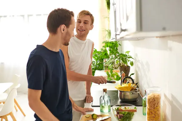 Two men share happiness in their modern kitchen as they prepare a healthy salad with fresh ingredients. — Stock Photo