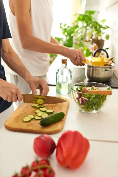 Dos hombres felizmente cortar verduras y hacer una ensalada de colores en su elegante cocina. - foto de stock
