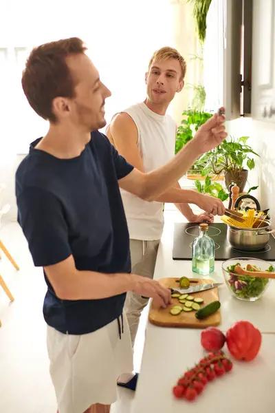 Two loving partners chop fresh vegetables and cook pasta, sharing laughter in their vibrant kitchen. — Stock Photo