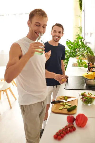 Two men happily chop vegetables and make a fresh salad, enjoying quality time together in their stylish kitchen. — Stock Photo