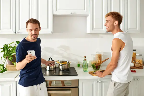 Due uomini che cucinano allegramente insieme in una cucina moderna, abbracciando il loro amore e creatività. — Foto stock