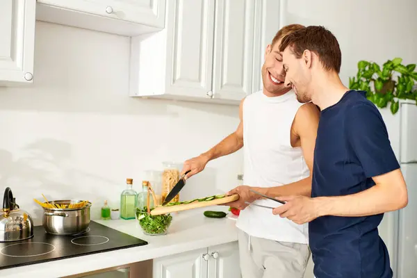 Two men happily collaborate in their stylish kitchen, and enjoying each others company. — Stock Photo