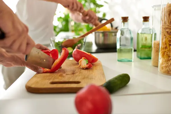 A happy couple skillfully cuts vibrant vegetables, creating a delicious salad in their cozy kitchen. — Stock Photo