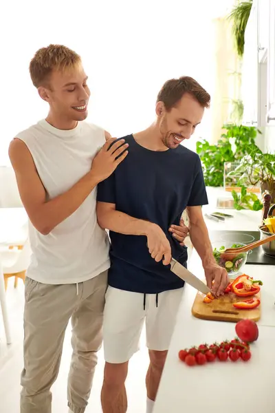 Two partners joyfully chop vegetables side by side, creating a delicious salad in their cozy kitchen. — Stock Photo