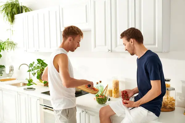 Two men enjoy a moment of love and joy while cooking a fresh salad together in their bright kitchen. — Stock Photo