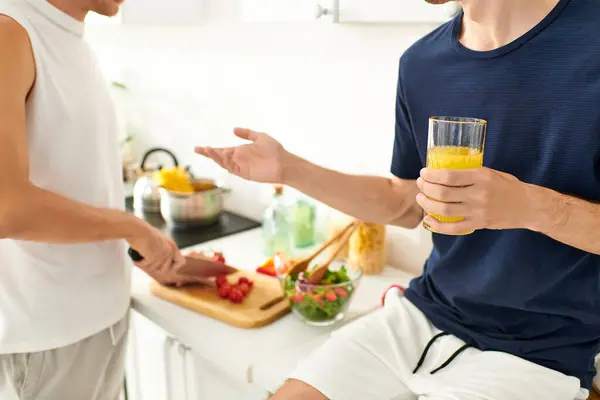 Um casal alegre colabora na cozinha, cortando legumes e criando uma salada vibrante juntos. — Fotografia de Stock