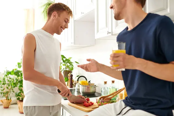 Una pareja cariñosa cocinan alegremente juntos, cortando verduras y preparando una ensalada vibrante en su cocina. - foto de stock