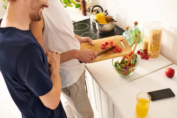 Em uma cozinha moderna, um alegre casal gay ri enquanto corta vegetais para uma salada refrescante.. — Fotografia de Stock