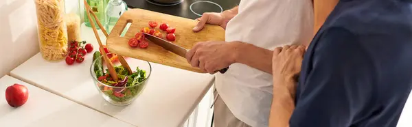 Um casal amoroso cozinha em conjunto, cortando legumes frescos e criando uma salada vibrante em sua cozinha elegante. — Fotografia de Stock