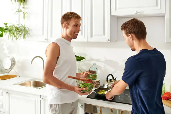 Una coppia amorevole si diverte a cucinare fianco a fianco, creando una vibrante insalata nella loro cucina. — Foto stock