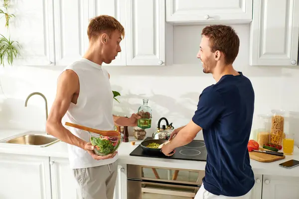 Two men happily cook together, and sharing laughter in their stylish kitchen. — Stock Photo