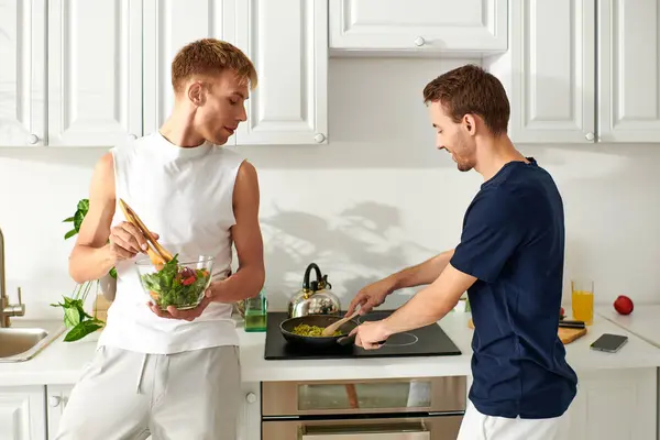 In una cucina elegante, due uomini condividono un momento gioioso mentre preparano un pasto sano insieme.. — Foto stock
