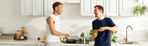 Two men happily prepare a fresh meal in their stylish kitchen, sharing love and laughter while cooking. — Stock Photo