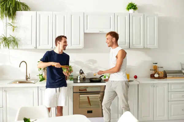 A happy couple prepares a meal, enjoying playful moments while cooking in their stylish kitchen. — Stock Photo