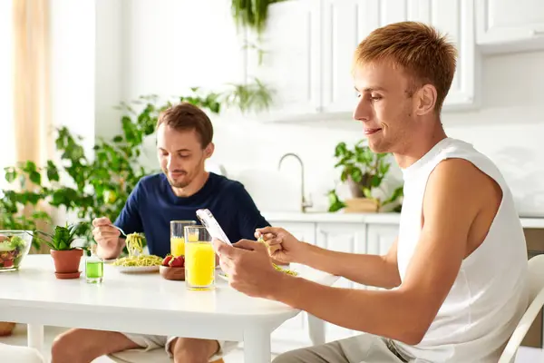 Two men happily eating together in their modern kitchen. — Stock Photo