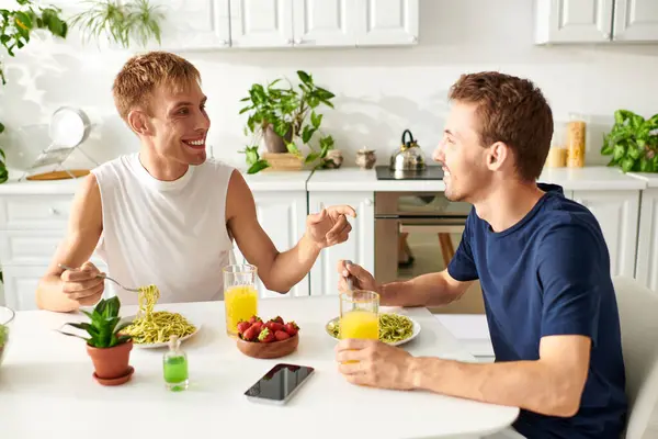 Um casal gay amoroso conversando e tendo delicioso almoço na cozinha — Fotografia de Stock