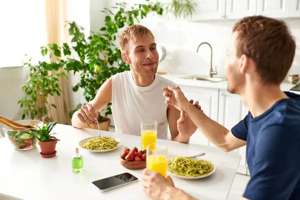 Una coppia gay felice che mangia in una cucina moderna, condividendo l'amore — Foto stock