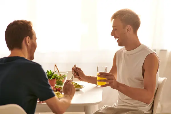 A happy couple eating tasty pasta together, enjoying each others company in a stylish kitchen. — Stock Photo