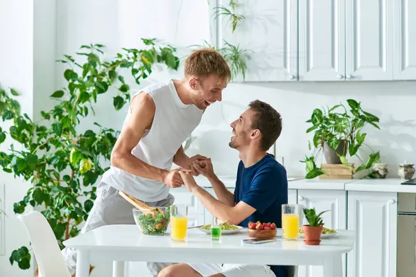 Two partners share a joyful moment while holding hands in their cozy, stylish kitchen. — Stock Photo