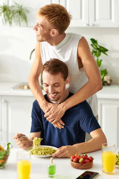 Una pareja amorosa sonriendo felizmente, compartiendo amor y alegría en su cocina moderna mientras almuerzan. — Stock Photo