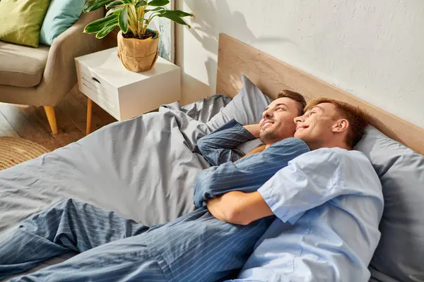 In a warm morning light, two partners in pajamas embrace joyfully while enjoying each others company. — Stock Photo