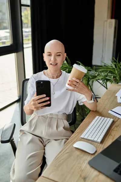 A fashionable young bald woman, dressed elegantly, multitasks with her coffee and smartphone. — Stock Photo