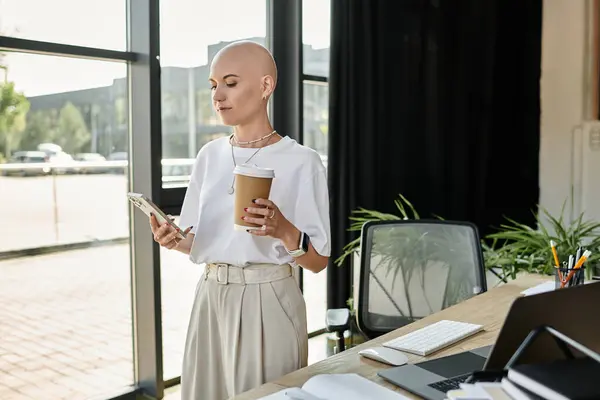 She stands with a coffee cup in one hand and a phone in the other, exuding confidence. — Stock Photo