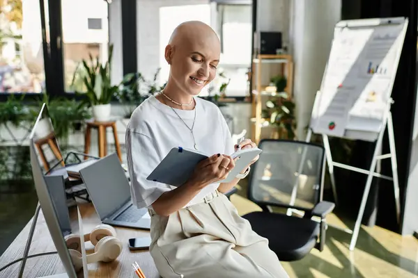 La femme dans des vêtements élégants sourit tout en notant des idées sur son espace de travail moderne. — Photo de stock