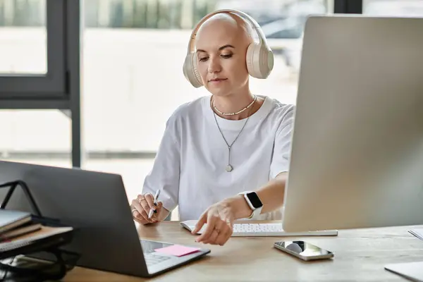 A young bald woman wearing elegant attire concentrates on her tasks while listening to music. — Stock Photo