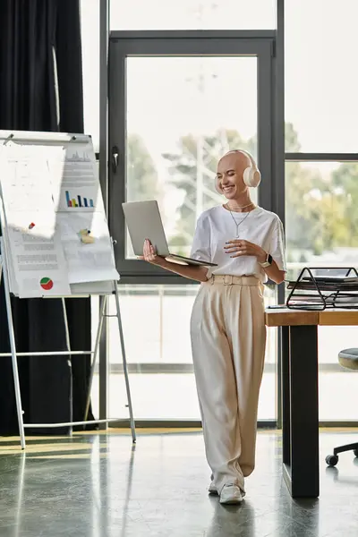 A young bald woman dressed elegantly interacts with a laptop in a stylish office setting. — Stock Photo