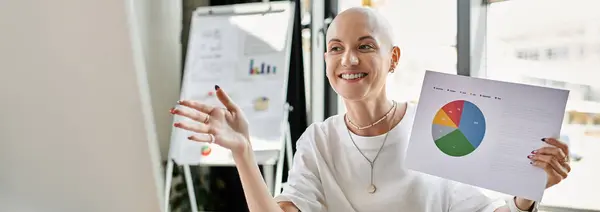 A woman with a bald head joyfully shares insights from a vibrant chart at a professional gathering. — Stock Photo