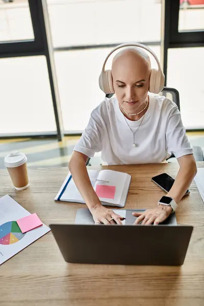 Dressed elegantly, a young bald woman focuses intently on her laptop, sipping coffee. — Stock Photo
